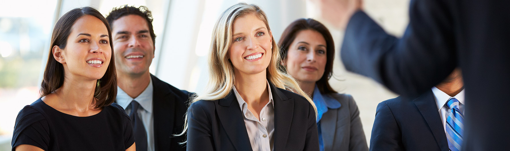 An audience of business people smiling at a presenter 